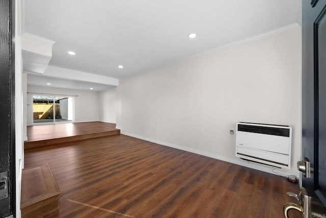 unfurnished room featuring heating unit, wood finished floors, baseboards, and ornamental molding