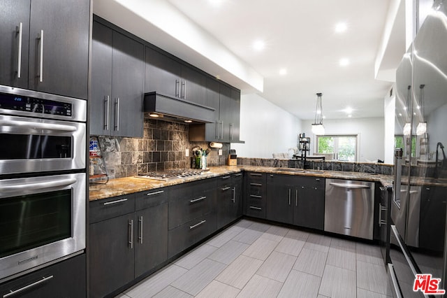 kitchen featuring pendant lighting, sink, tasteful backsplash, light stone counters, and stainless steel appliances