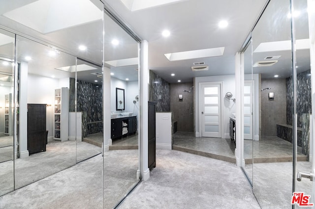 bathroom with a skylight, vanity, and walk in shower