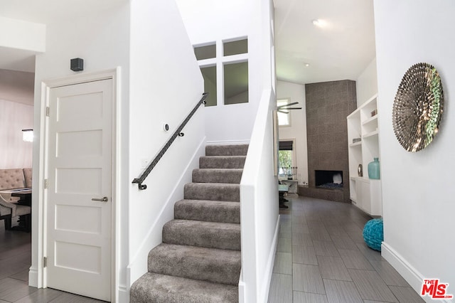 staircase featuring hardwood / wood-style floors, ceiling fan, and a fireplace