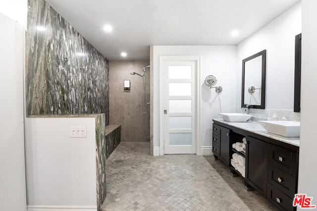 bathroom with tile patterned flooring, vanity, and tiled shower