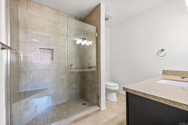 bathroom with tile patterned flooring, vanity, a shower with shower door, and toilet