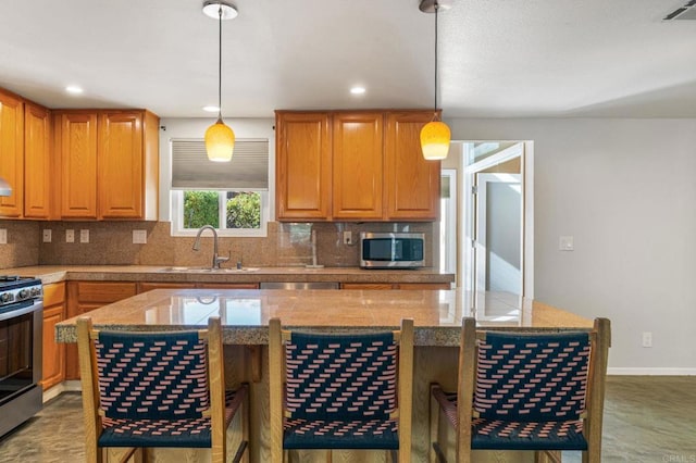 kitchen with hanging light fixtures, light stone countertops, sink, and appliances with stainless steel finishes