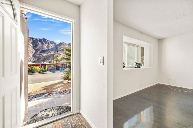 foyer entrance with a mountain view, a healthy amount of sunlight, and a textured ceiling