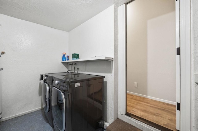 washroom with washing machine and dryer, a textured ceiling, and hardwood / wood-style flooring