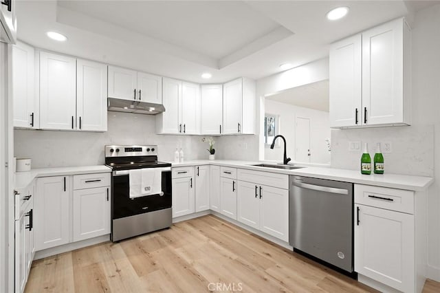 kitchen with white cabinets, stainless steel appliances, light hardwood / wood-style floors, and sink