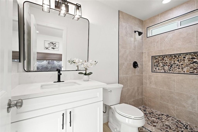 bathroom with vanity, toilet, and a tile shower