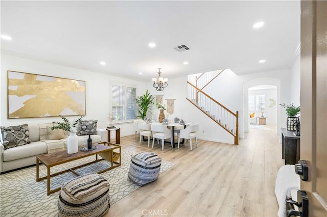 living room featuring crown molding, light wood-type flooring, and an inviting chandelier