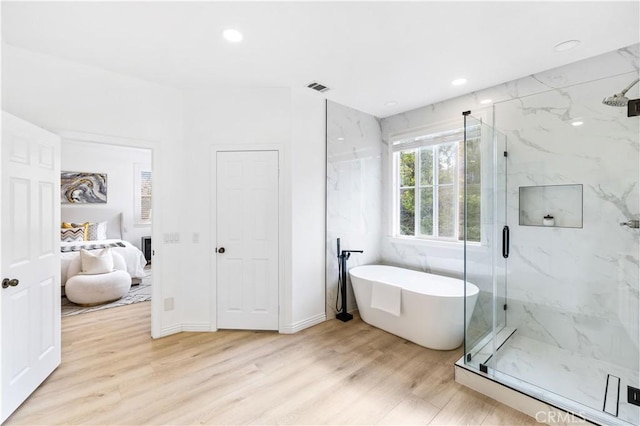 bathroom with wood-type flooring and shower with separate bathtub