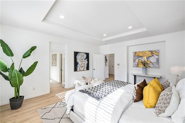 bedroom with a raised ceiling and light hardwood / wood-style floors