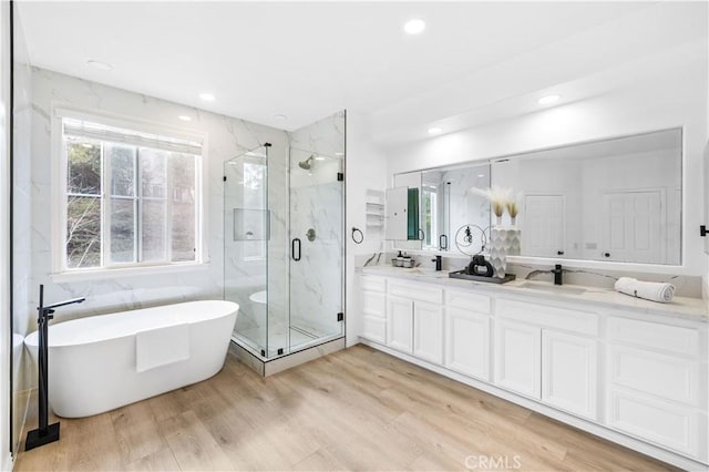 bathroom featuring independent shower and bath, hardwood / wood-style flooring, and vanity