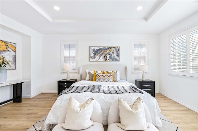 bedroom with light hardwood / wood-style flooring and a raised ceiling