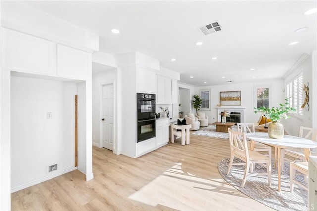 kitchen featuring light wood-type flooring, white cabinetry, and black double oven