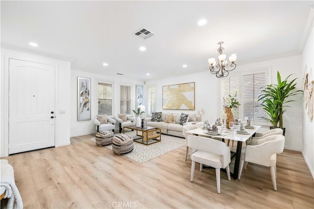 dining space with a notable chandelier, ornamental molding, and light hardwood / wood-style floors