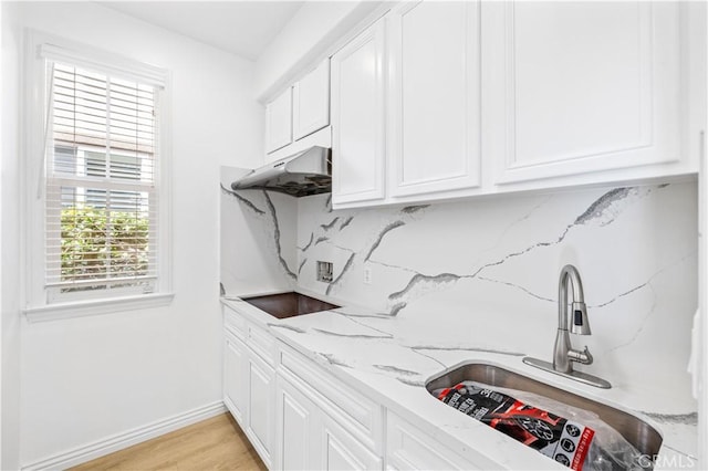 kitchen with white cabinets, light stone countertops, sink, and black electric stovetop