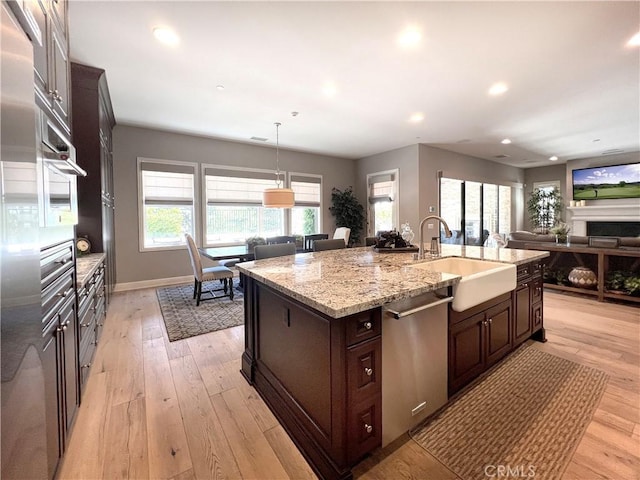 kitchen featuring dishwasher, light wood-type flooring, sink, and a kitchen island with sink