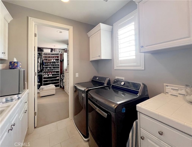 laundry area with light tile patterned flooring, cabinets, and independent washer and dryer