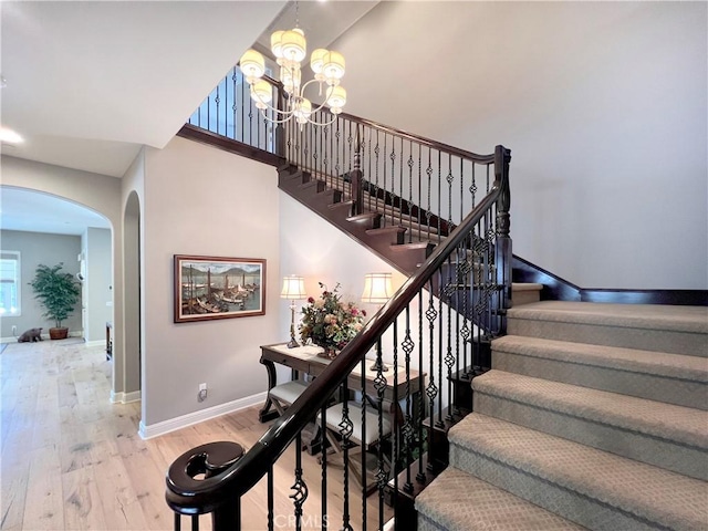 staircase featuring wood-type flooring and a chandelier