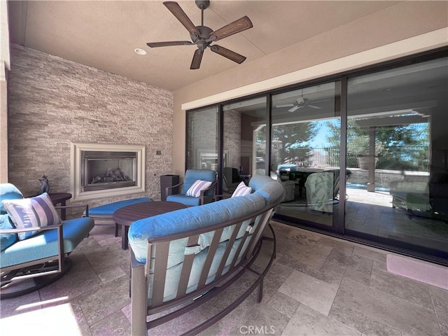 view of patio with an outdoor living space with a fireplace and ceiling fan