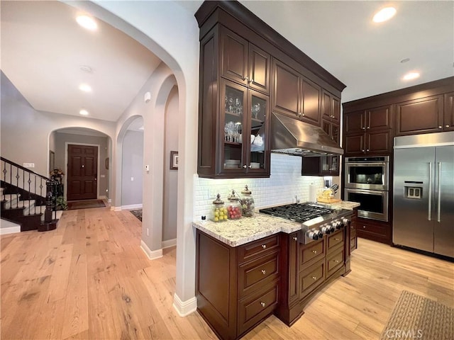 kitchen with dark brown cabinetry, stainless steel appliances, and light hardwood / wood-style flooring