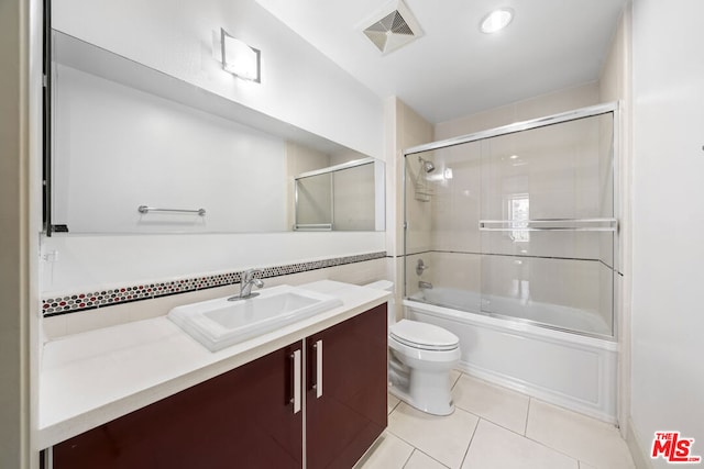 full bathroom featuring tile patterned flooring, vanity, toilet, and bath / shower combo with glass door