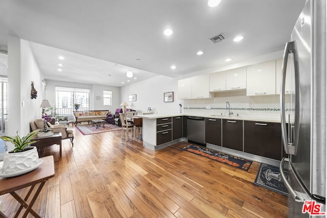 kitchen with dark brown cabinetry, sink, light hardwood / wood-style floors, white cabinets, and appliances with stainless steel finishes