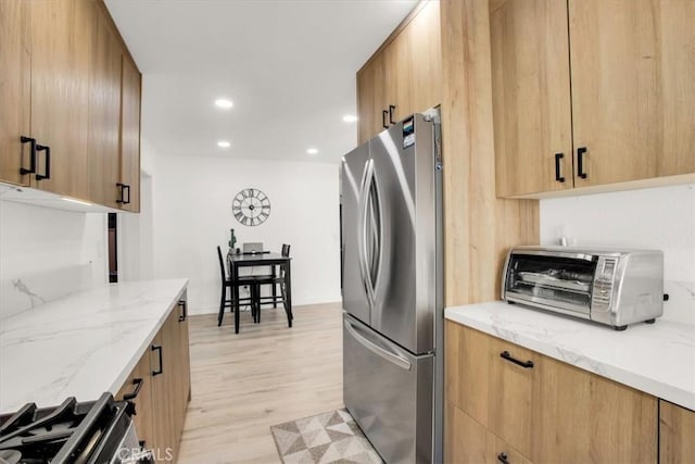 kitchen featuring light stone counters, light wood-type flooring, and appliances with stainless steel finishes