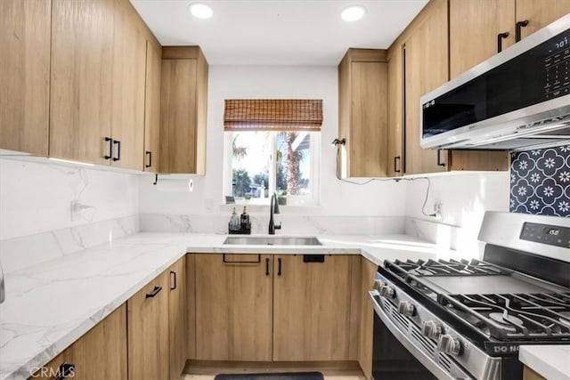 kitchen with light stone counters, sink, decorative backsplash, and stainless steel appliances