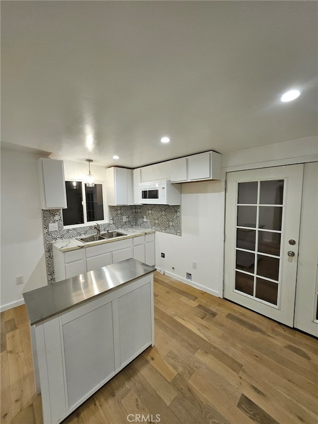 kitchen with tasteful backsplash, a center island, light hardwood / wood-style floors, sink, and white cabinets