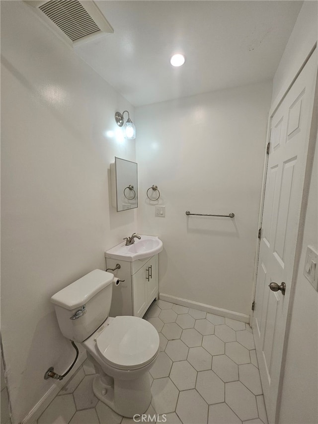 half bath with toilet, baseboards, visible vents, and vanity