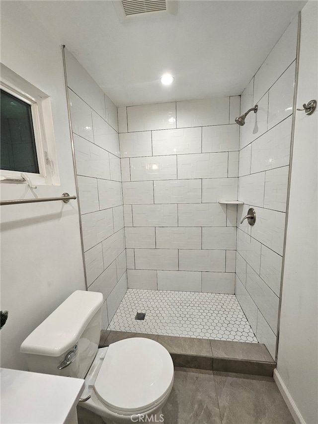 bathroom featuring toilet and a tile shower