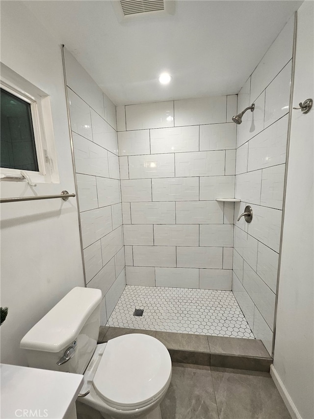 bathroom with visible vents, toilet, and tiled shower