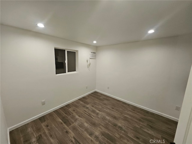 spare room with an AC wall unit and dark hardwood / wood-style floors