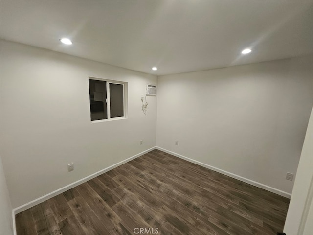 empty room with recessed lighting, a wall mounted air conditioner, dark wood finished floors, and baseboards