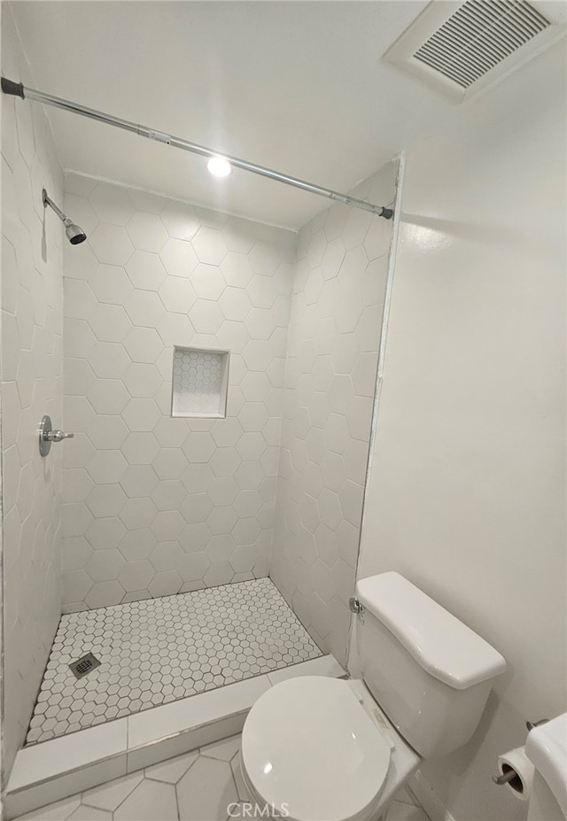 bathroom featuring toilet, a stall shower, and visible vents