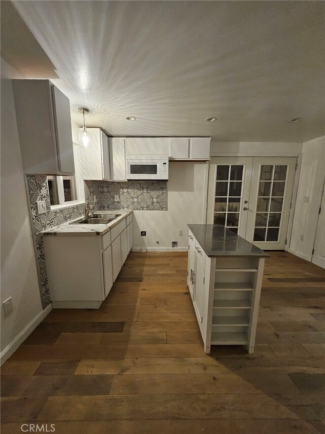 kitchen with decorative light fixtures, dark wood-type flooring, sink, and white cabinetry