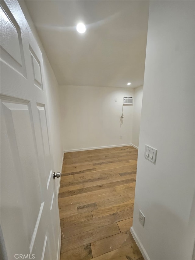 unfurnished room with light wood-type flooring and a wall mounted air conditioner