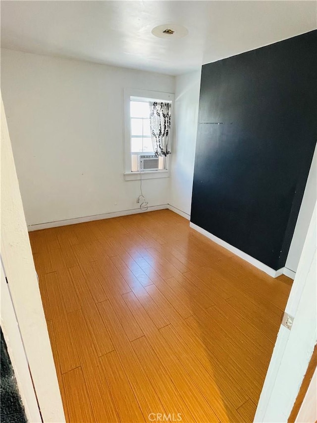 spare room with baseboards and wood finished floors