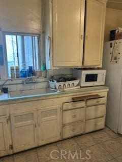 kitchen featuring light tile patterned flooring, white appliances, and sink