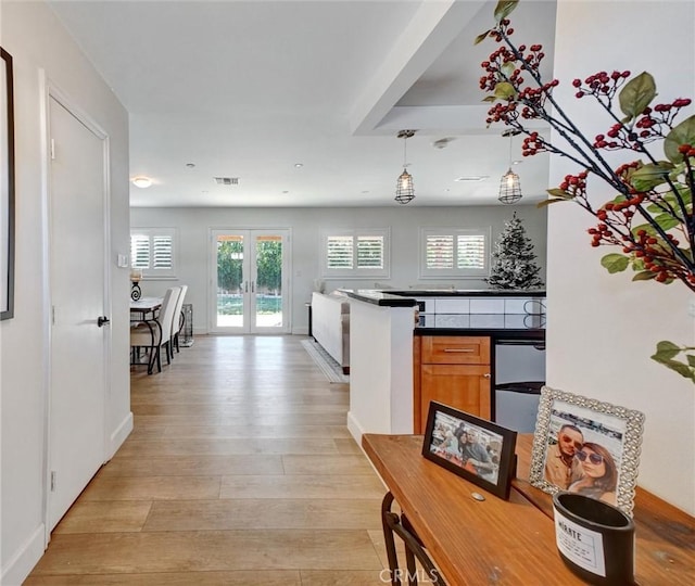 kitchen featuring hanging light fixtures, french doors, and light hardwood / wood-style flooring