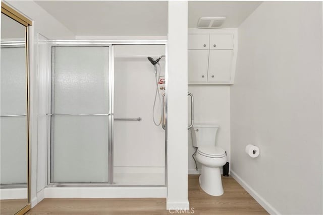 bathroom featuring hardwood / wood-style floors, toilet, and walk in shower