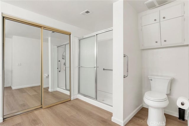 bathroom featuring hardwood / wood-style flooring, toilet, and an enclosed shower