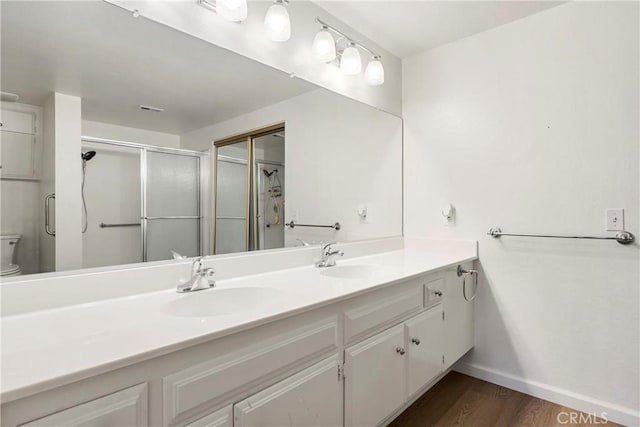 bathroom featuring hardwood / wood-style floors, vanity, a shower with shower door, and toilet