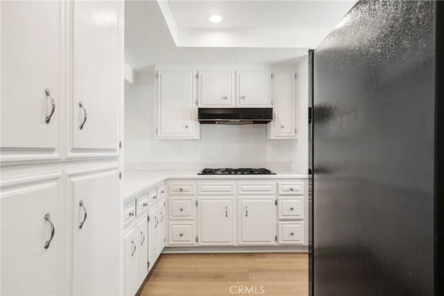 kitchen featuring black refrigerator, white cabinetry, gas cooktop, and light hardwood / wood-style flooring