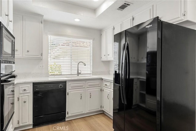 kitchen with black appliances, white cabinets, light wood-type flooring, and sink