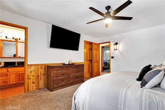 carpeted bedroom with ceiling fan and wood walls