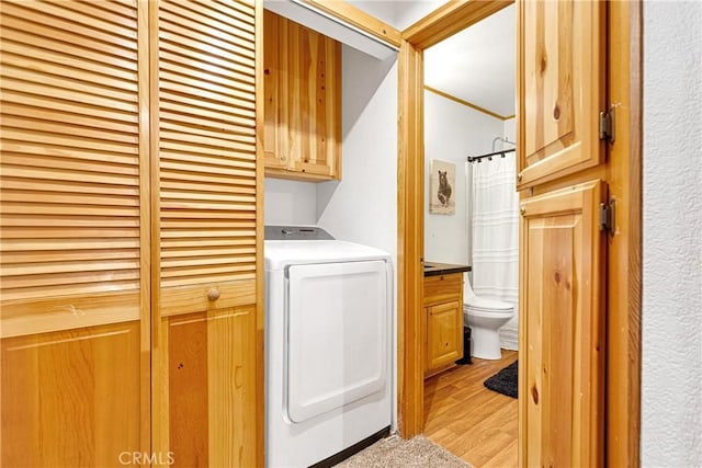 laundry area with cabinets, washer / dryer, and light wood-type flooring