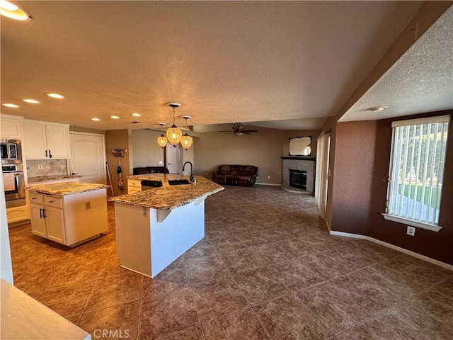 kitchen featuring white cabinetry, sink, hanging light fixtures, a center island with sink, and appliances with stainless steel finishes