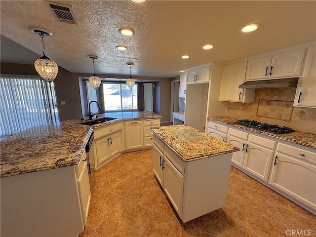 kitchen featuring sink, a center island, hanging light fixtures, stainless steel gas cooktop, and backsplash