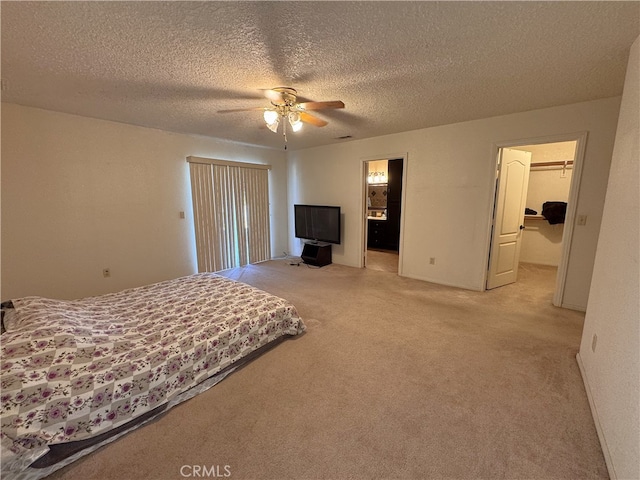 carpeted bedroom featuring a walk in closet, a textured ceiling, a closet, and ceiling fan